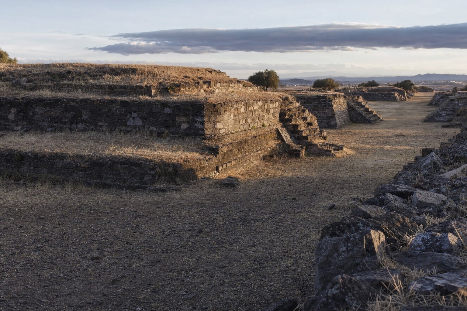 Ruined platforms along the Avenue of the Dead at Teotihuacan under a low sun