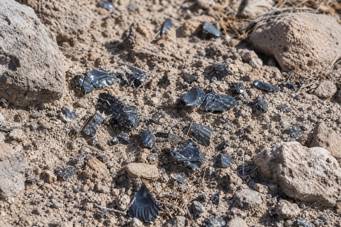 Fragments of black obsidian scattered in the dry ground at Teotihuacan
