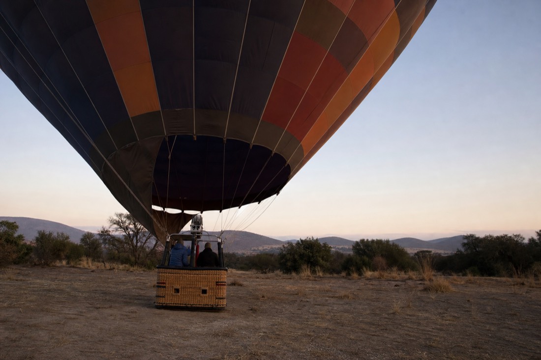 A small two-person hot air balloon basket at dawn on a Teotihuacan field